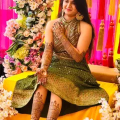 A beautiful bride posing with her hand and leg mehendi. The designs are coordinated, and she looks absolutely radiant for her mehendi ceremony.