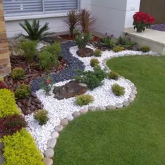 Here, I used a combination of hardscaping and softscaping to create a low-maintenance, visually interesting garden bed. The contrasting colors and textures of the white and black pebbles create a dry riverbed effect, bordered by carefully selected shrubs and grasses.