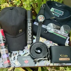 A full gift set for the stylish man in your life. This hamper includes a personalized wallet, a branded shirt, a leather belt, a watch, a cap, sunglasses, and other assorted gifts, all in a sleek black theme.