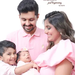 Welcoming a new baby is a joy for the entire family. This portrait, with its soft pink color palette, captures the happy moment when an older sibling meets the newest family member.