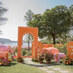 The vibrant entrance to a 'Pyaar ka Pind' Haldi ceremony in Udaipur. Whimsical pink elephants and bold orange arches welcome guests to a celebration filled with color, energy, and a modern take on Punjabi traditions.