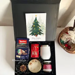 A festive Christmas hamper filled with goodies like Loacker wafers, Country Bean coffee, and a decorative candle, all presented with a 'Merry Christmas' card.