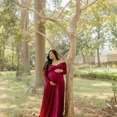 Embracing the glow of motherhood in a vibrant red gown. This outdoor portrait in a lush green park makes the color pop beautifully.