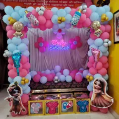 A cozy baby shower setup for a home celebration. We decorated the seating area with a pink and blue balloon frame, a 'Baby Shower' neon sign, and cute character props.