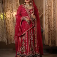 A classic red bridal lehenga with a modern twist. The dark blue border adds a unique contrast, while the detailed embroidery ensures you look and feel like royalty on your wedding day.