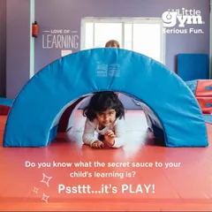 A young girl peeks out from under a soft play tunnel, her eyes full of curiosity. We use play-based learning to make every activity an adventure, teaching problem-solving and spatial awareness.