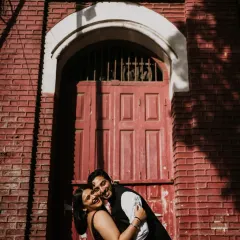 A moment of pure joy and laughter against a vibrant red brick wall. This candid shot perfectly captures the couple's playful energy and the city's colourful character.