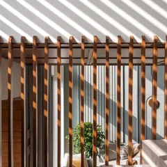 **Amber House, Ahmedabad:** A close-up of the wooden screen shows how simple elements can create dynamic patterns. As light filters through, the shadows become a moving piece of art on the walls, constantly changing the feel of the space throughout the day.