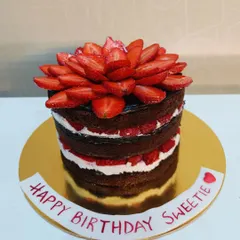 This is my naked cake with chocolate and fresh strawberries. The layers of rich chocolate cake, white cream, and sliced strawberries are left exposed for a rustic and beautiful look.