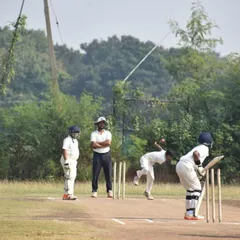 A young bowler in action during a match on our Hyderabad tour, with the coach observing from the umpire's position.