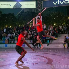 Freezing a dramatic, mid-air moment from a Kalaripayattu martial arts display. This type of fast-action photography is crucial for covering live performances and cultural events.