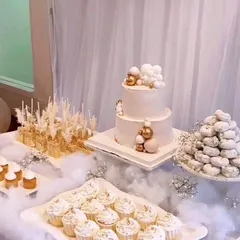 A dreamy, all-white dessert table that looks like it's floating on clouds. I used soft cotton batting, sheer white drapes, and a selection of elegant white and gold desserts to create this heavenly theme for a special celebration.