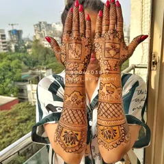A personalized bridal mehndi with the couple's initials "N" and "N" prominently featured on the palms. The design is a mix of geometric checks and lotus motifs on the arms.