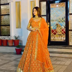 A full-length view of the stunning orange and gold lehenga. It’s a bright, cheerful outfit that will make you stand out at any festive occasion.