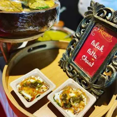A live station serving Palak Patta Chaat, where crispy spinach leaves are topped with yogurt and chutneys. This is a modern and popular twist on a classic street food.