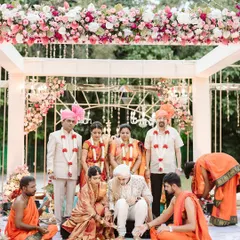 A beautiful moment from the wedding ceremony, with the family gathered under the elegant floral mandap. The overhead arrangement of pink and white roses created a soft and romantic canopy for the rituals.