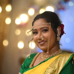 A close-up of a bride's Vidhi look, featuring a beautiful smile and glowing makeup. The bokeh background highlights the bride's features and the detailed work on her nath and bindi.