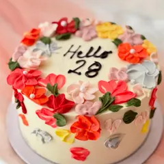 A vibrant birthday cake decorated with colorful palette knife buttercream flowers. The abstract, textured floral design gives it a modern and artistic feel.