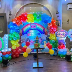 The complete Cocomelon party setup, including a themed cake table, character cutouts, and a large light-up number '1'.