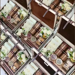 An overhead view of our classic wedding trunk boxes, prepared for a bulk order. Each trunk is filled with an assortment of treats and flowers, demonstrating our commitment to quality and consistency for large-scale wedding gifting.