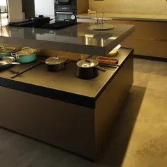 This kitchen showcases a stunning two-level island, perfect for both meal prep and casual dining. The warm, ambient lighting and mix of wood and stone textures create an inviting atmosphere, making it the true heart of the home.