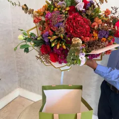 Meet my signature 'Bouquet in a Bag'. This isn't just a bouquet; it's a complete gift, ready to be presented. A burst of bold, beautiful colours, artfully arranged and placed in our custom green tote, makes for an unforgettable dinner party offering.