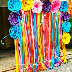 A vibrant and colorful photo backdrop made of rainbow ribbons and large paper flowers. This is a simple yet highly effective way to create a cheerful and eye catching photo corner.