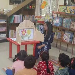 We use special tools like this traditional wooden puppet stage to make stories even more magical. Here, children are captivated as illustrations come to life, drawing them deeper into the narrative.