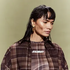 One of the models styled in a layered plaid look for the Huemn show, embodying a cool, androgynous aesthetic.