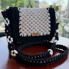 My classic black and white sling bag. The strap is decorated with delicate white macrame flowers, making it a truly unique piece.