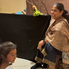 Sharing a moment with a young audience member and a parrot puppet during a birthday party. I always try to make my performances for children interactive and personal.
