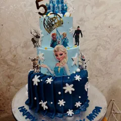 A grand three-tier Frozen cake for a 5th birthday. This impressive cake features Elsa, Anna, Olaf, and Sven, with a beautiful ice castle and edible snowflakes creating a winter wonderland.