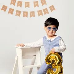 Three cheers for turning three! Dressed in a dapper outfit with a number 3 balloon, this little man is ready to celebrate his third birthday in style against a clean, classic studio backdrop.