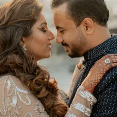 An intimate close-up from Dhwani and Riten's Sangeet night. The focus is on their connection, with her henna-adorned hand gently touching his shoulder.