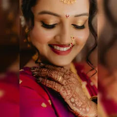 A detailed shot of a Marathi bride's fresh and dewy makeup, focusing on the flawless golden eyeshadow, defined lashes, and traditional nose ring.