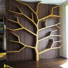 An example of my custom furniture capabilities. This unique tree-shaped bookshelf was built with plywood against a dark wood veneer wall, serving as both a functional storage unit and a piece of art.
