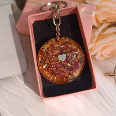 This round keychain was made from a client's flowers and personalized with the initials 'N' and 'F'. It's a lovely way for a couple to share a memory.