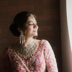 Heritage redefined for the modern bride. This bride is captured in a moment of quiet reflection, wearing an elaborate silver-toned polki set that stands out against her embroidered pink lehenga.