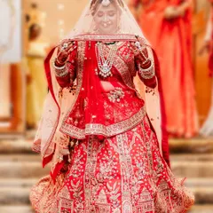 The moment of the bridal entry. The bride looks down shyly under her veil, her intricate red lehenga on full display. This is a classic and timeless shot that every bride treasures.