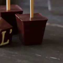 A close-up of our solid chocolate blocks on a stick, embossed with the L'inoui 'L'. These are the key to a rich, authentic hot chocolate, free from artificial syrups or powders.