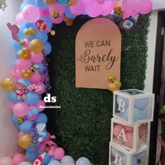 Here is a popular baby shower theme we created, perfect for a gender reveal or welcoming a new arrival. The setup includes a pink and blue balloon arch against a green wall, a custom "We Can Barely Wait" sign, and transparent 'BABY' blocks filled with matching balloons.