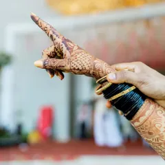 A creative shot focusing on the bride's intricate henna design and traditional bangles.