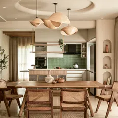 This shot from the AD feature shows the open dining and kitchen area. The design uses sculptural wooden pendant lights and cane chairs to create a cohesive, wabi-sabi inspired environment.