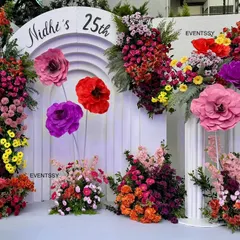 A closer view of the floral backdrop, showing the artful arrangement of flowers and oversized paper blooms against the white arches.