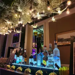 A beautifully styled bar is key to any great party. Here, the bar is set under a canopy of baby's breath and illuminated birds, creating a magical spot for guests to gather and enjoy their drinks.
