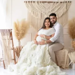 A happy couple sharing a moment in our boho-chic studio setup. This popular theme uses natural textures like macrame and pampas grass to create a warm, stylish, and intimate atmosphere for your maternity photoshoot.