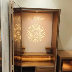 A close-up of the mandir with its doors open, revealing the 'Om Namah Shivay' mantra and beautiful backlighting. The design includes small shelves for idols and drawers for storing pooja essentials.