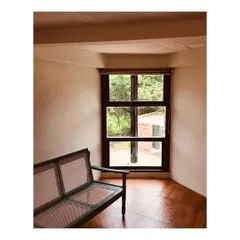 A quiet seating nook with a cane bench is perfectly positioned to look out at the surrounding nature. This space was designed for relaxation and to blur the line between the indoor living space and the outdoor environment.