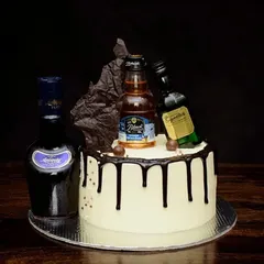 A sophisticated drip cake for a whiskey connoisseur. This design is topped with miniatures of Antiquity, Black & Milds, and Signature, complete with a dark chocolate sail for extra drama.