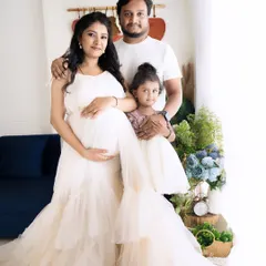 A beautiful family portrait with the parents and their daughter, all dressed in coordinating cream outfits, creating a harmonious and loving image.